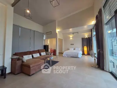 Spacious modern living room with cozy seating and elegant bedroom area