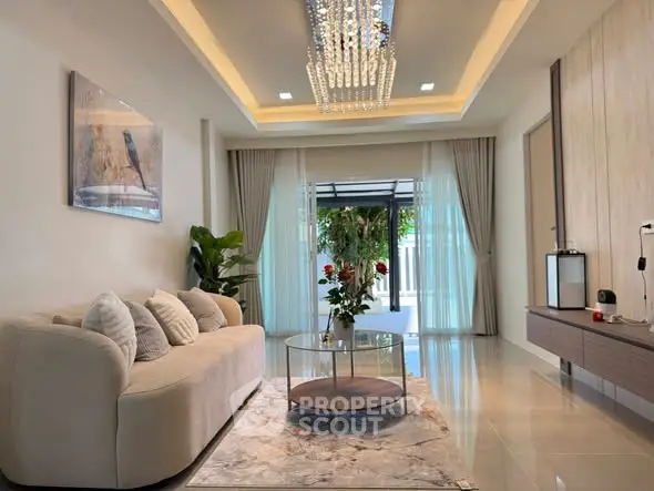 Luxurious living room with elegant chandelier and modern decor, featuring a cozy sofa and glass coffee table.