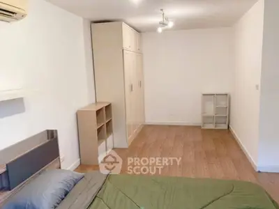 Spacious bedroom with wooden flooring and modern furniture in a minimalist style.