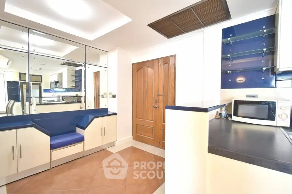 Modern kitchen with sleek cabinetry and built-in seating, featuring a microwave and ample counter space.