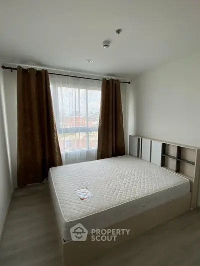 Spacious bedroom with large window and natural light, featuring a comfortable bed and modern decor.