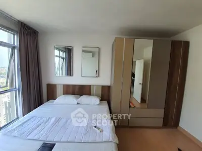 Modern bedroom with large window and stylish wardrobe, offering a cozy and bright living space.