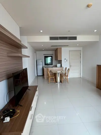 Modern open-plan living room with sleek kitchen and dining area, featuring contemporary furniture and bright lighting.