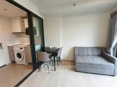 Modern apartment with open kitchen and cozy living area featuring a washing machine and stylish furniture.