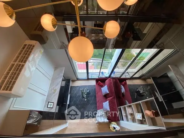 Stunning modern living room with high ceiling and elegant decor, featuring a cozy red sofa and large windows.