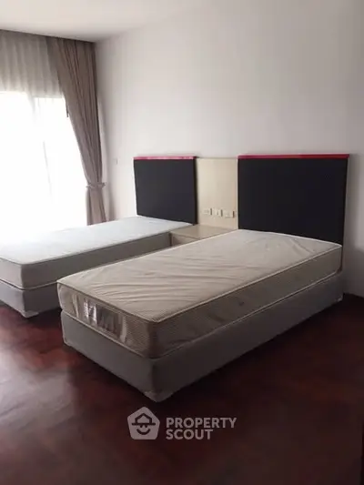 Spacious bedroom with twin beds and natural light from large window.