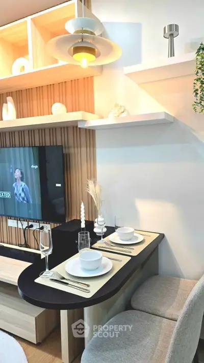 Modern living room with stylish dining setup and wall-mounted TV, featuring elegant lighting and decor.