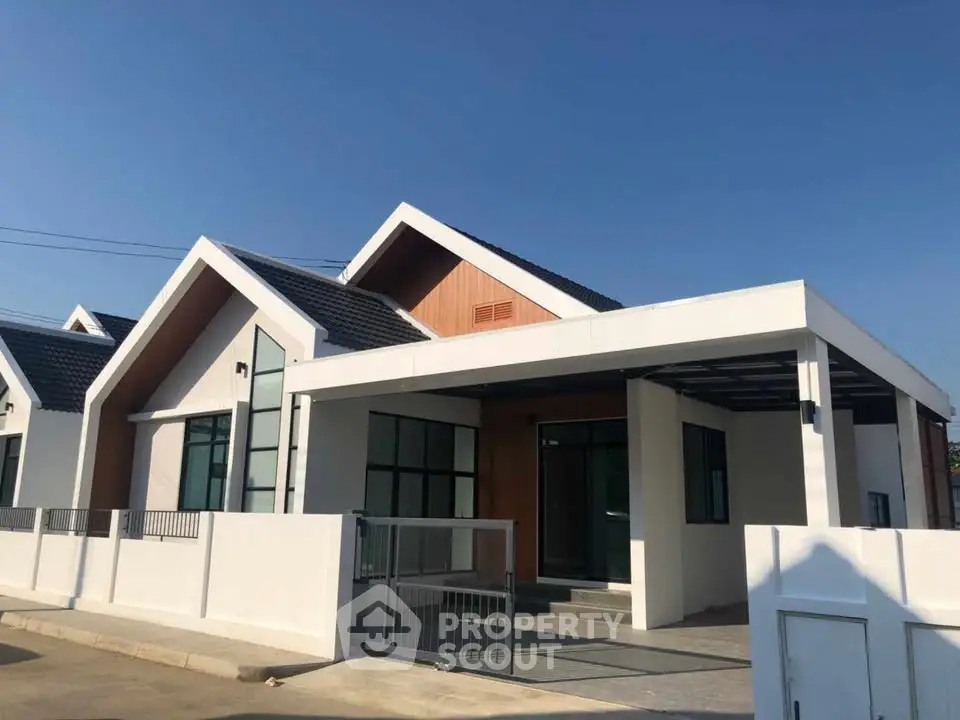 Modern minimalist house with sleek design and spacious driveway under clear blue sky.