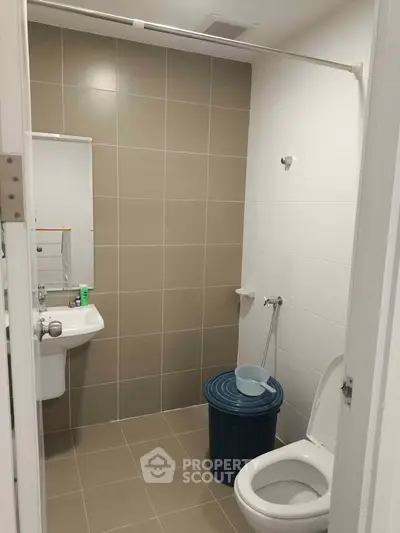 Modern bathroom with sleek tiles and essential fixtures in a contemporary apartment.