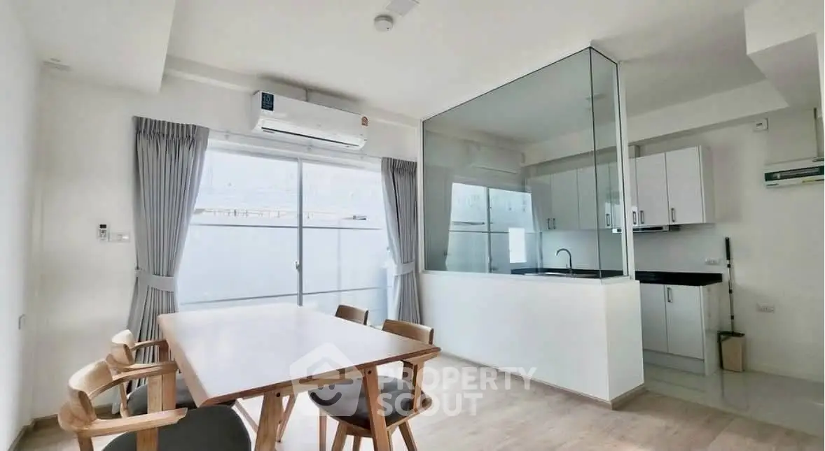 Modern dining area with glass partition and sleek kitchen design