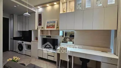 Modern living room with sleek cabinetry, integrated appliances, and stylish decor in a compact apartment.