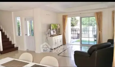 Spacious living room with modern decor and large windows opening to a garden view.