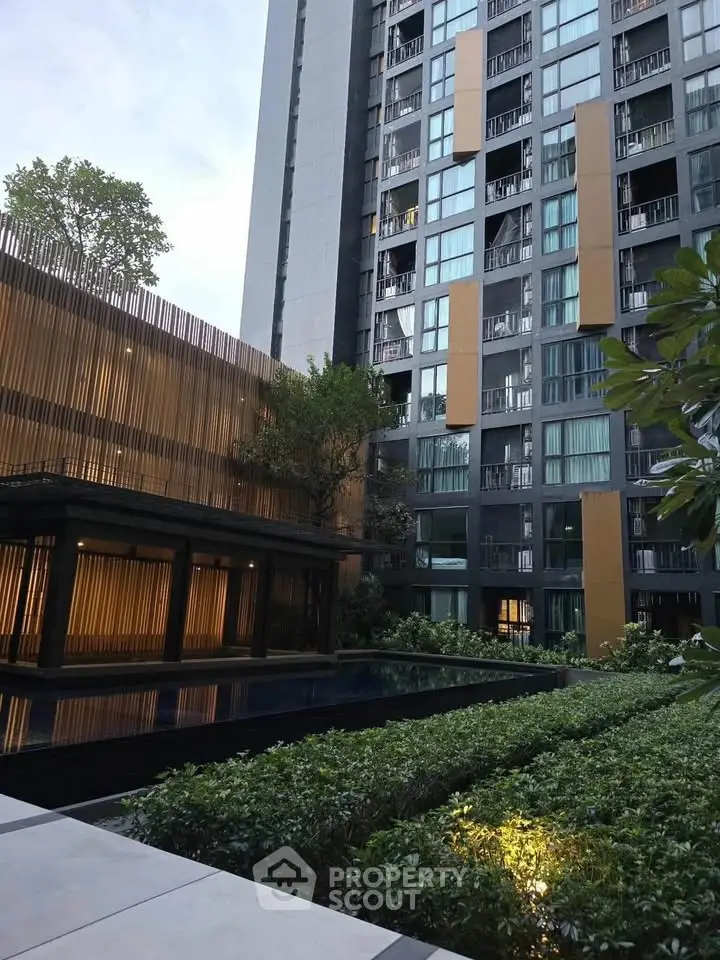 Modern high-rise building with lush garden and serene pool area