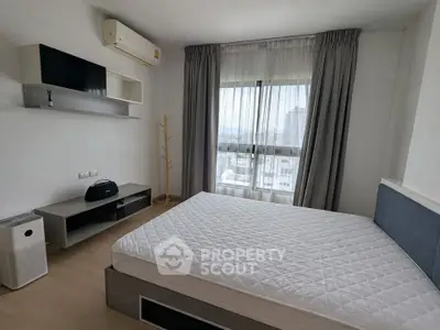 Modern bedroom with large window and minimalist decor in a high-rise apartment.