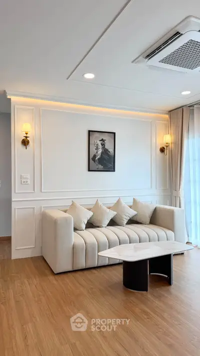 Elegant living room with modern sofa, stylish wall art, and natural light from large windows.