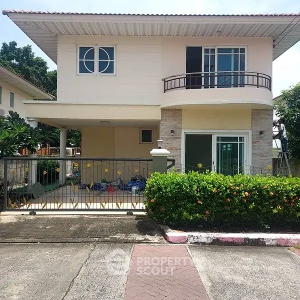 Charming two-story house with balcony and lush greenery in a serene neighborhood.