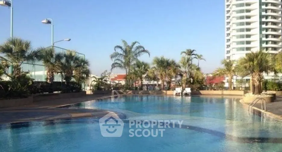 Luxurious residential pool area with palm trees and high-rise building view.