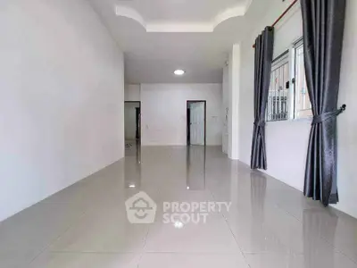 Spacious modern living room with glossy tiled floors and large window with curtains.