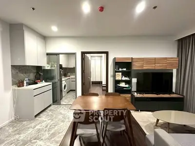 Modern open-plan living room with dining area and kitchen featuring sleek design and contemporary furniture.