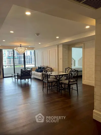 Spacious living room with elegant decor and city view, featuring hardwood floors and modern furniture.