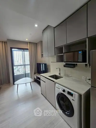 Modern apartment kitchen with washing machine and sleek cabinetry