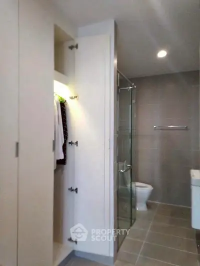 Modern bathroom with sleek design, featuring a glass shower and built-in wardrobe.