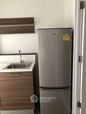 Modern kitchen with sleek fridge and stylish cabinetry in a contemporary apartment.