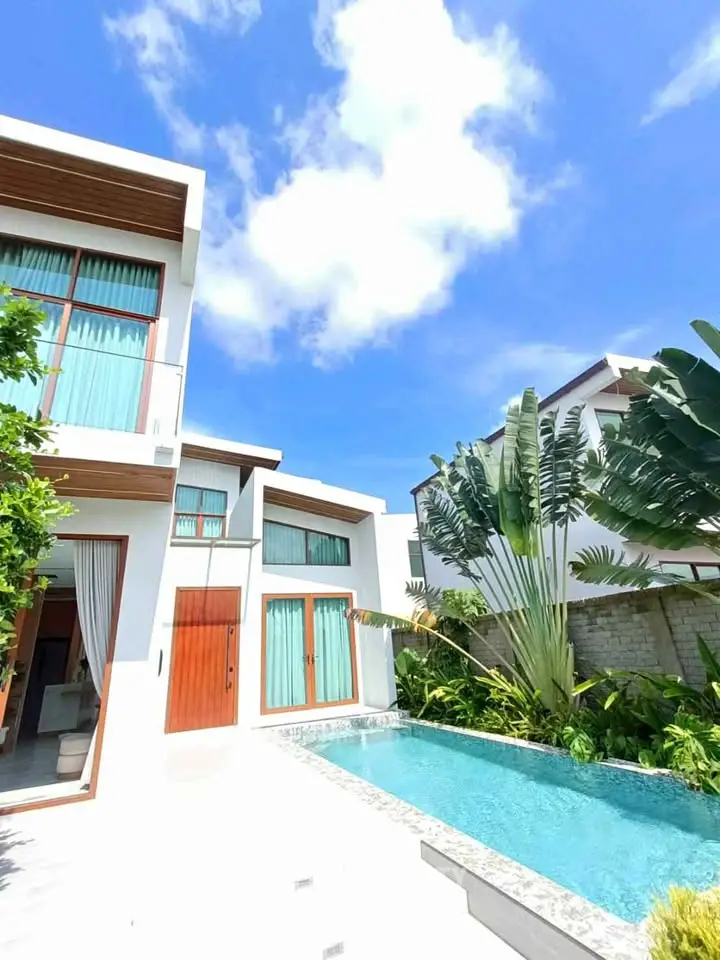 Luxurious modern villa with private pool and lush garden under a clear blue sky.