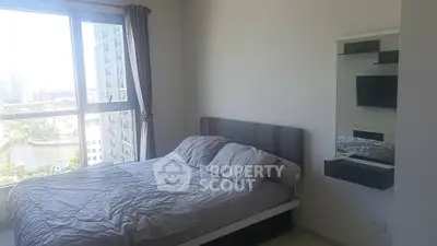 Modern bedroom with large window offering city view, featuring a cozy bed and wall-mounted TV.