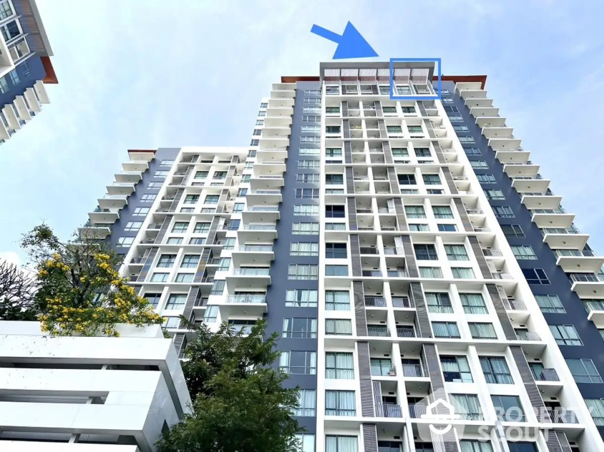 Modern high-rise residential building with blue sky backdrop, showcasing contemporary architecture and spacious balconies.