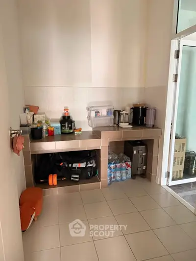 Compact kitchen area with tiled floor and modern appliances, ideal for efficient cooking and storage.
