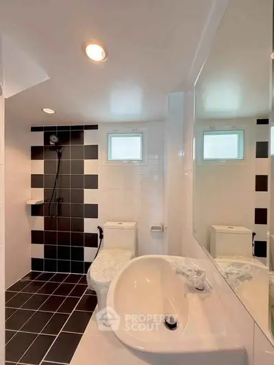 Modern bathroom with sleek black and white tiles and contemporary fixtures.