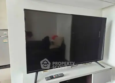Modern living room with sleek flat-screen TV and remote on a stylish stand.