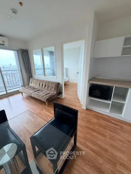 Modern apartment interior with open living room and kitchen, featuring city view.