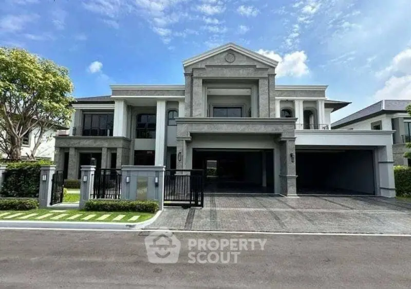 Luxurious modern mansion with grand entrance and spacious driveway under clear blue sky.