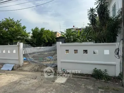 Spacious residential plot with boundary wall and lush greenery, ideal for custom home building.