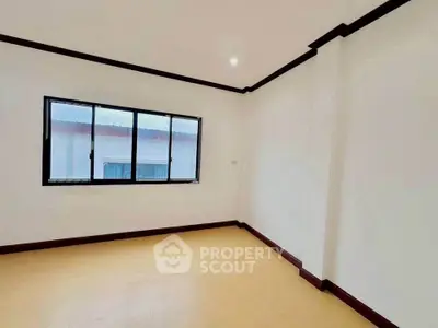 Spacious empty room with large window and wooden flooring, ideal for customization.