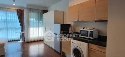 Modern kitchen with washing machine and microwave in a cozy apartment setting.