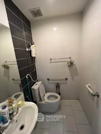 Modern bathroom with sleek black and white tiles, featuring a toilet and sink.