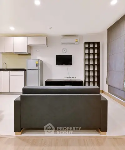 Modern living room with sleek furniture and open kitchen layout in a stylish apartment.