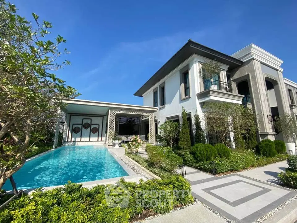 Luxurious modern villa with private pool and lush garden under clear blue sky.