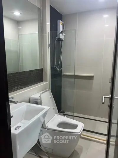 Modern bathroom with sleek fixtures and glass shower enclosure.