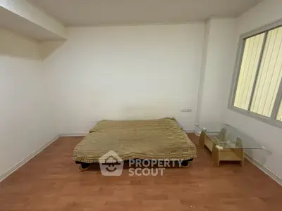 Minimalist bedroom with wooden flooring and simple furnishings