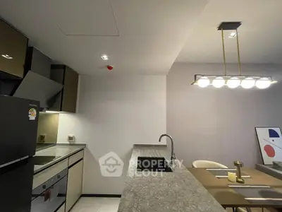 Modern kitchen with sleek design, featuring granite countertops and contemporary lighting.