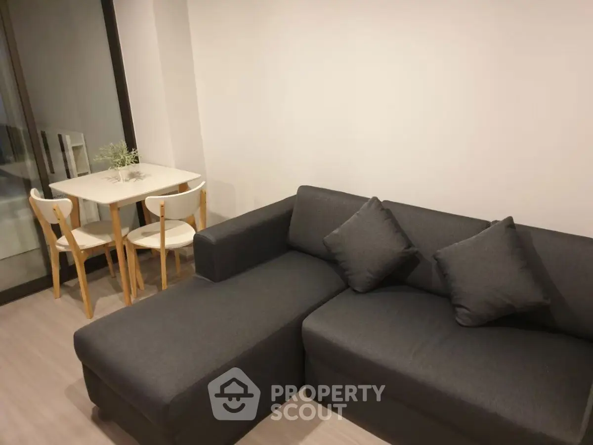 Modern living room with sleek dark sofa and cozy dining area, perfect for urban living.