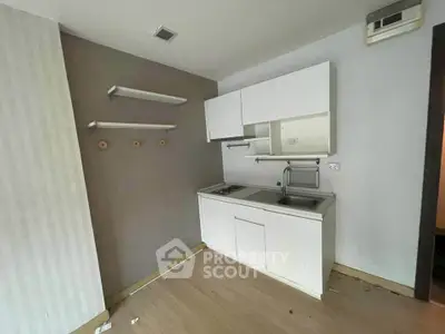 Compact kitchen with white cabinets and open shelving in modern apartment