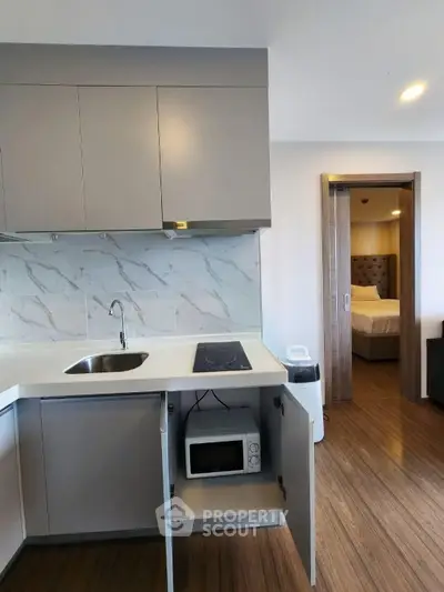 Modern kitchen with sleek cabinetry and open layout leading to a cozy bedroom, perfect for urban living.