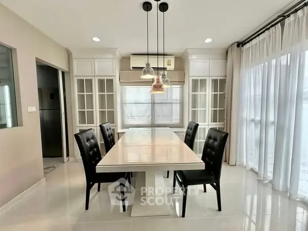 Elegant dining room with modern table and chairs, featuring large windows and stylish lighting.