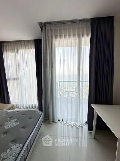 Spacious bedroom with ocean view and elegant curtains, featuring a comfortable bed and sleek flooring.