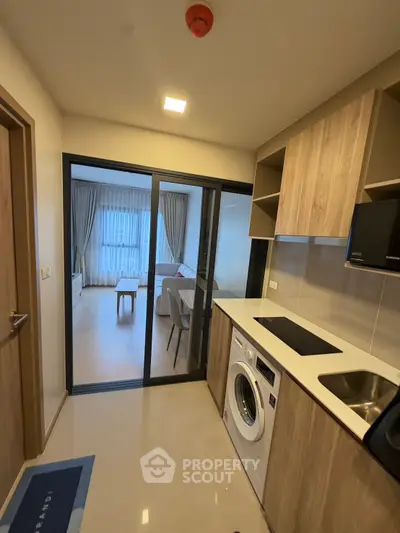 Modern kitchen with washing machine and open layout leading to cozy living room.